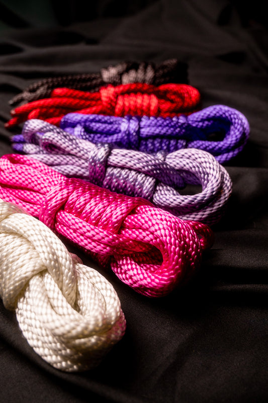 product photo of six 15 foot bundles of nylon rope in vampyre black, ritual red, purple passion, ultraviolet kiss, pink pleasure, and lunar white on top of a black sheet.